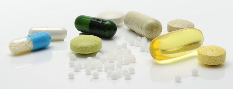 Close-up of various pills and capsules on a white surface, representing healthcare.